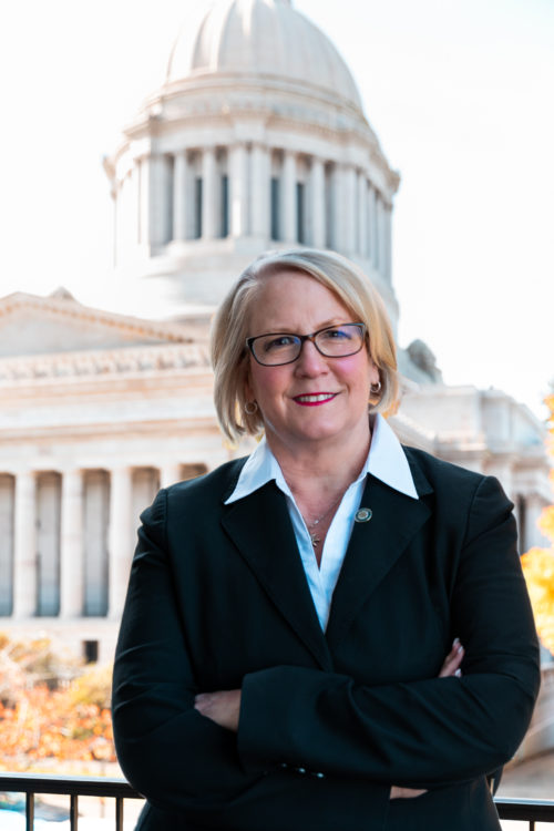Washington State Auditor Pat McCarthy stands with the state Capitol building in the background.