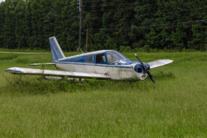 Abandoned blue and white single prop plane in green grass field
