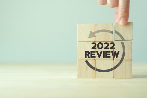 A person stacking square blocks, which read "2022 review."