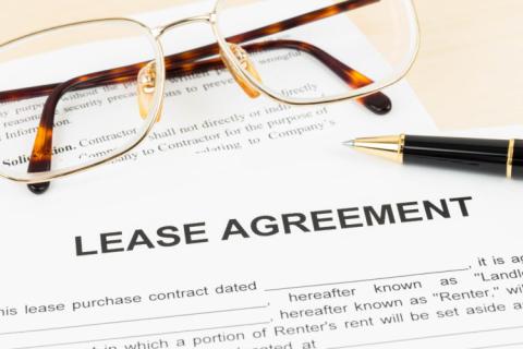 A lease agreement shown with a pair of eyeglasses and a pen