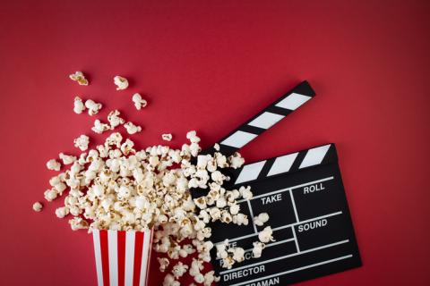 A photograph featuring a bucket of popcorn and a blank movie clapperboard.