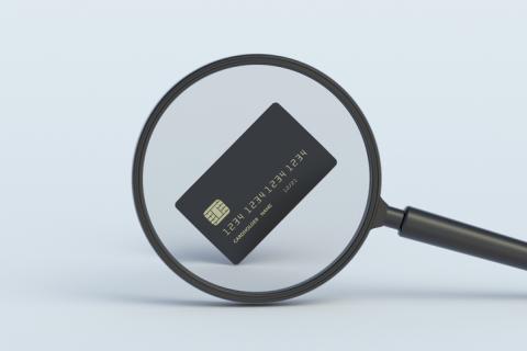 A photograph of a magnifying glass examining a credit card.