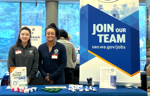 two SAO staffers standing next to banner that reads Join Our Team