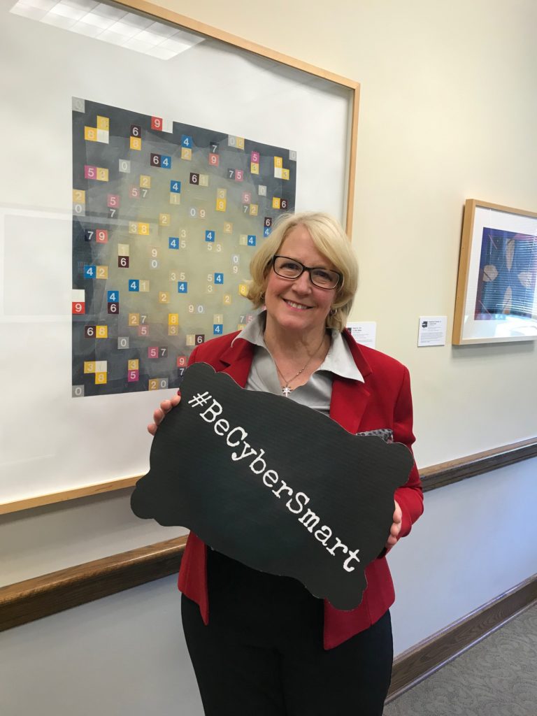 Washington State Auditor Pat McCarthy holds up a #BeCyberSmart sign.